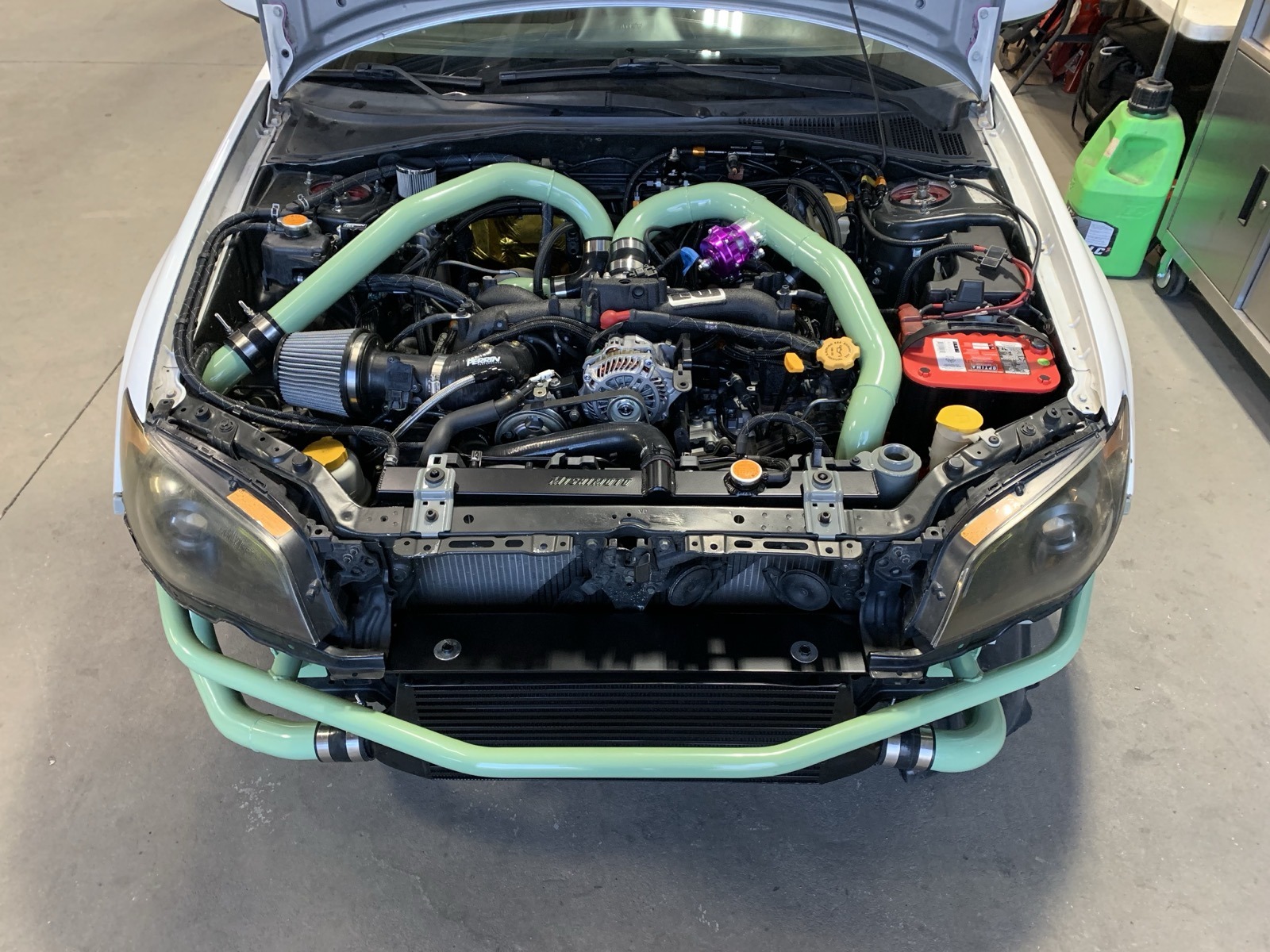 Subaru engine bay with teal powder coated parts Denver