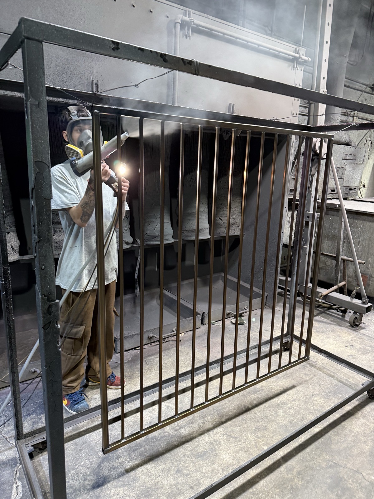 Metal gate being powder coated in booth Denver